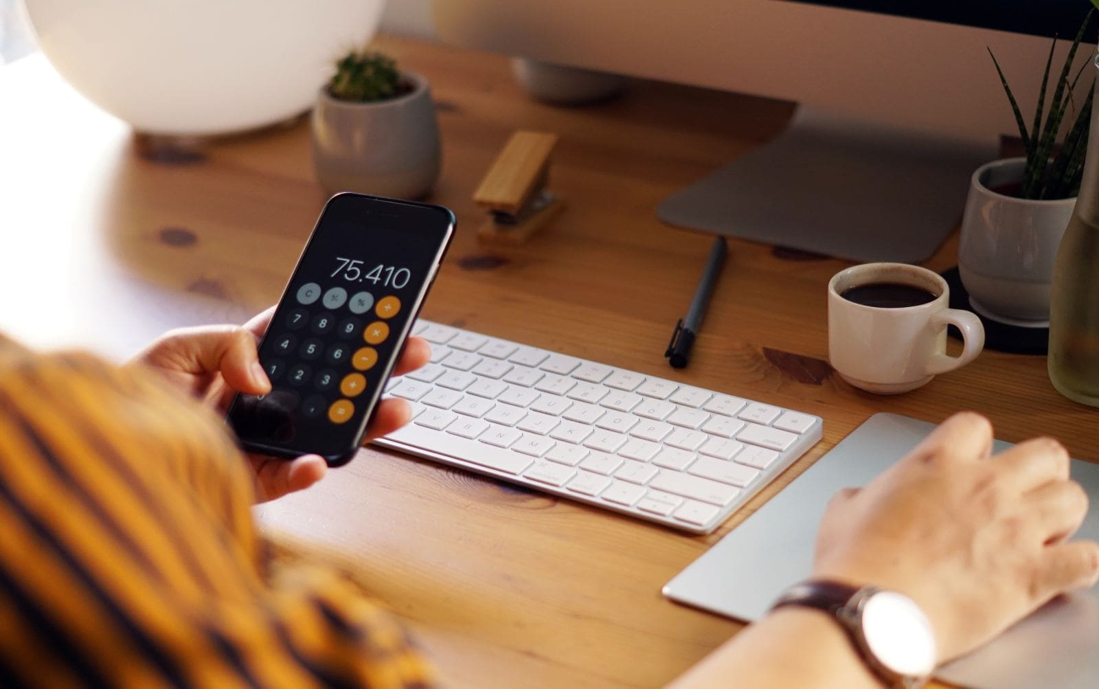 Woman typing on calculator at desk